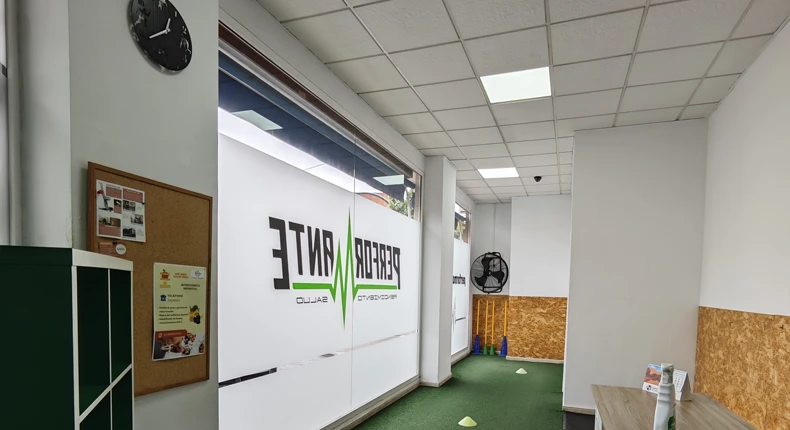 Entrada del gimnasio Performante con vinilos en el cristal y zona de césped artificial para entrenamiento funcional